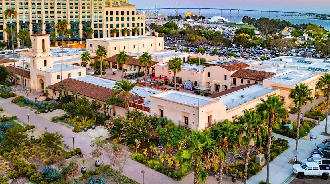 Aerial view of the five buildings and red-tile roofs with San Diego Bay beyond