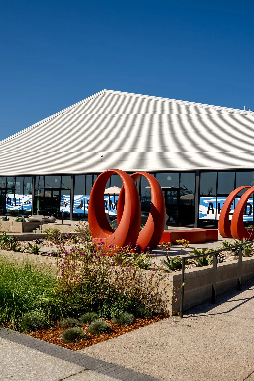 Red sculptural rings in front of a white-roofed pavilion